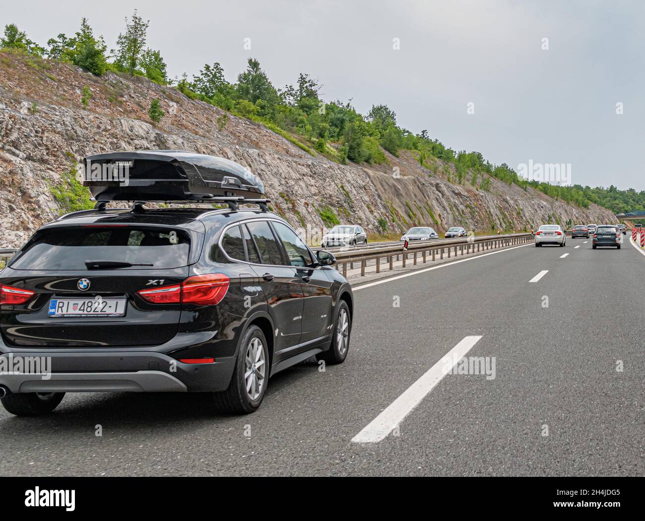 Una BMW X1 con un portapacchi e altre auto guidano lungo l'autostrada a Plitvice, Croazia. Foto Stock
