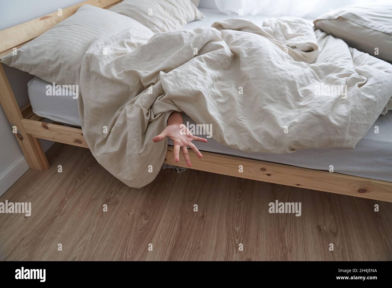 Primo piano della mano di un bambino, sdraiato a letto la mattina, la mano che sporge da sotto la coperta. Foto di alta qualità Foto Stock