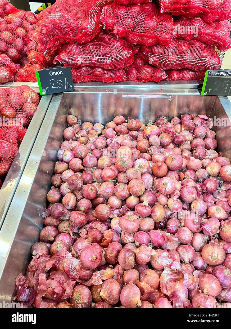 Mucchio di cipolle biologiche crude tenute in un cestino in una stalla di mercato Foto Stock