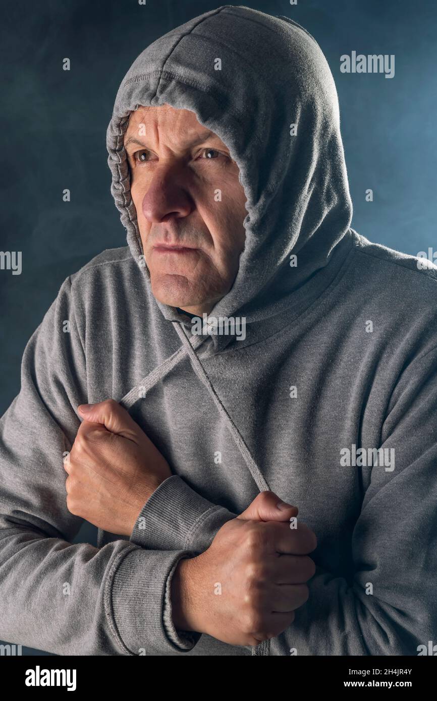 Un uomo bianco di mezza età indossa una felpa con cappuccio per proteggersi dal freddo e dalla nebbia Foto Stock