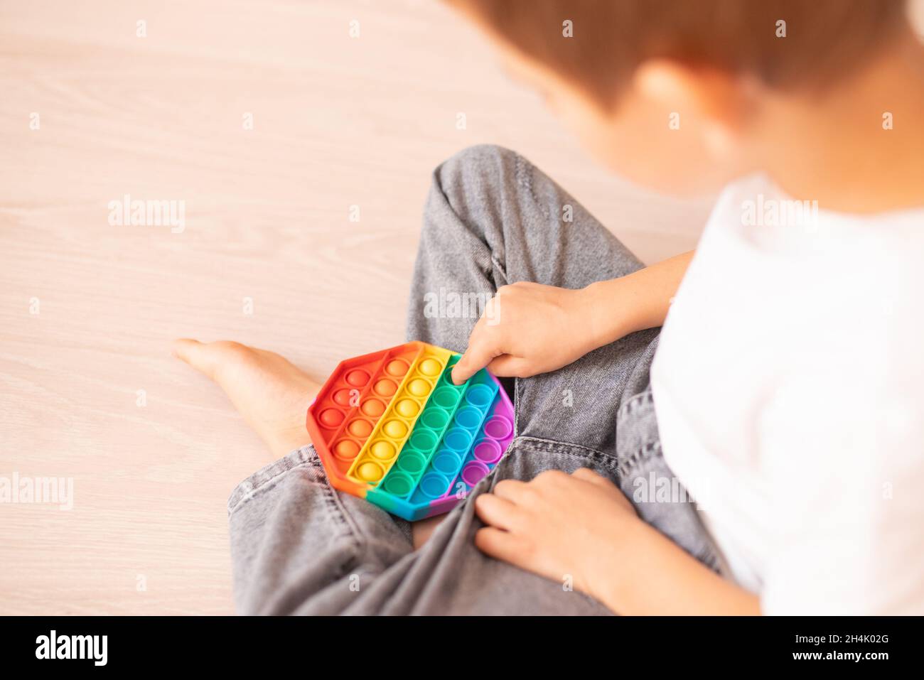 Un bambino con un colorato gioco pop IT. Anti-stress. Popolare giocattolo rilassante in silicone a forma di rombo stress. Giochi per bambini durante la quarantena e. Foto Stock