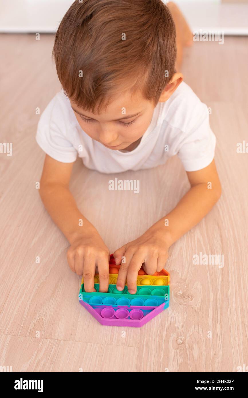 Un bambino con un colorato gioco pop IT. Anti-stress. Popolare giocattolo rilassante in silicone a forma di rombo stress. Giochi per bambini durante la quarantena e. Foto Stock