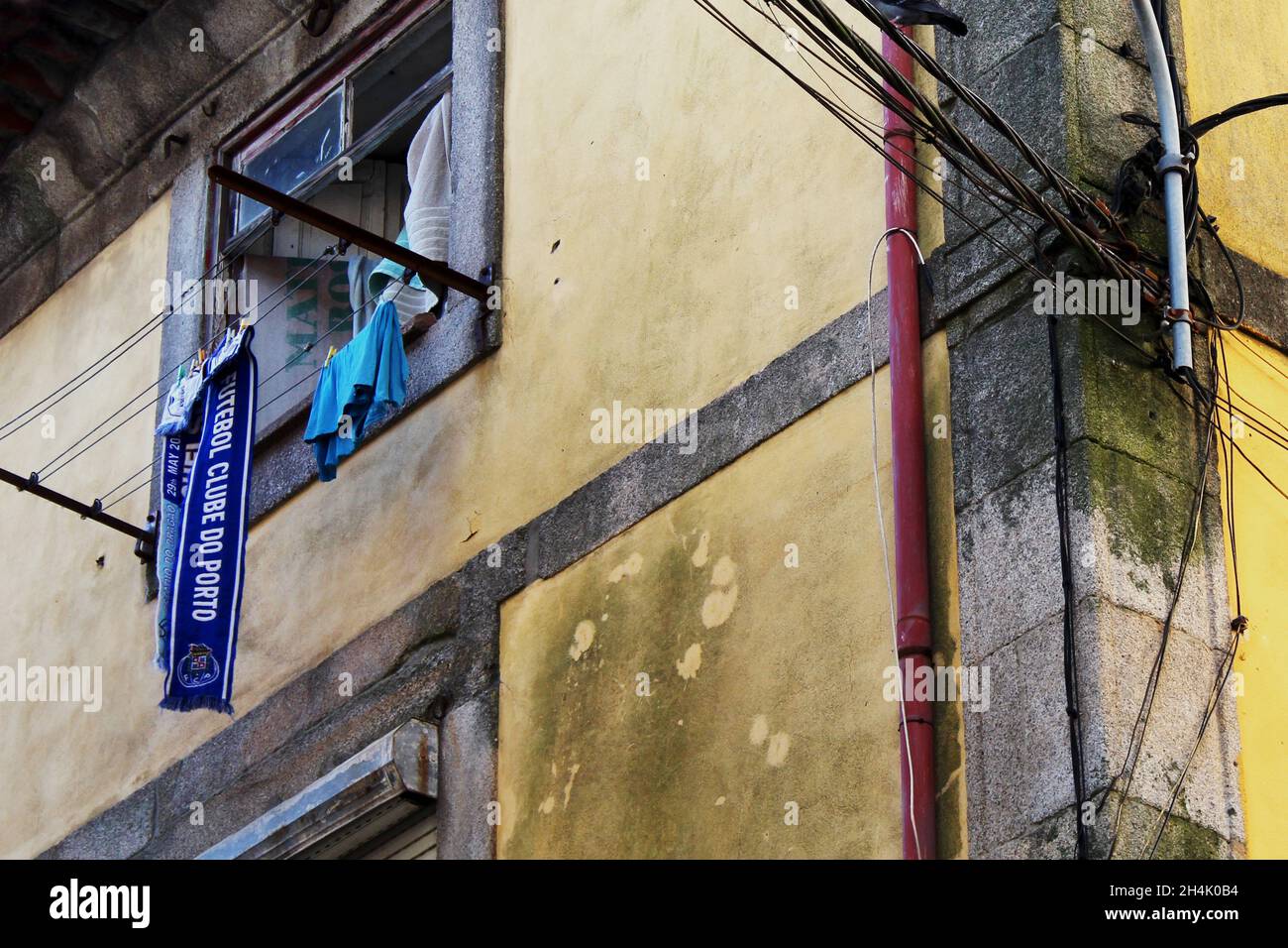 ein blauer Fanschall des Clube do Porto und ein blaues Shirt rocknen an einer Wäscheleine, die an einer gelben alten Hauswand angebracht ist. Porto. Foto Stock