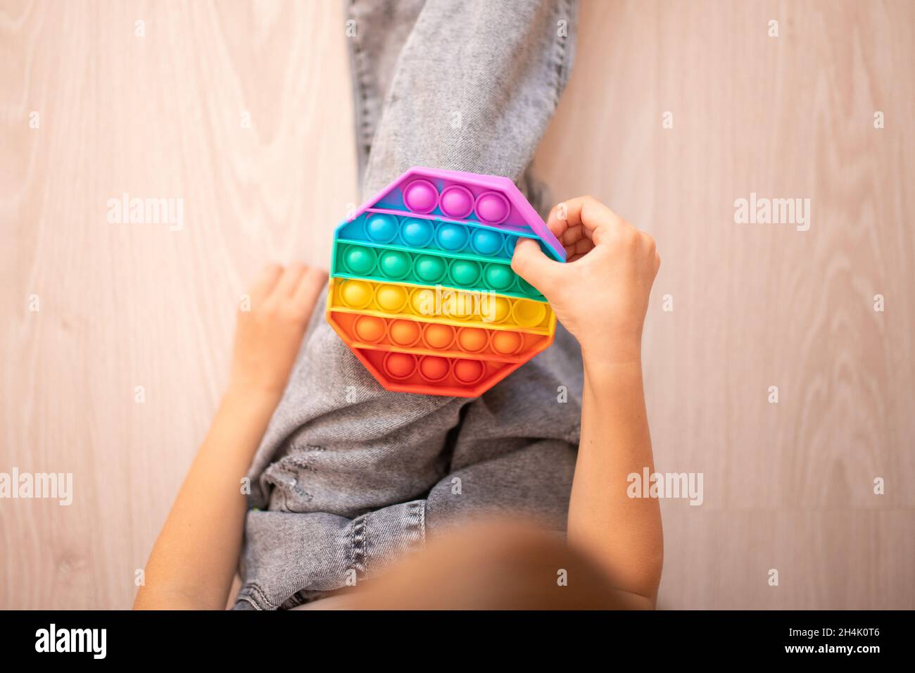 Primo piano delle mani dei bambini che giocano con il giocattolo colorato pop it fidget. Anti-stress. Popolare giocattolo rilassante in silicone a forma di rombo stress. Giochi per Foto Stock