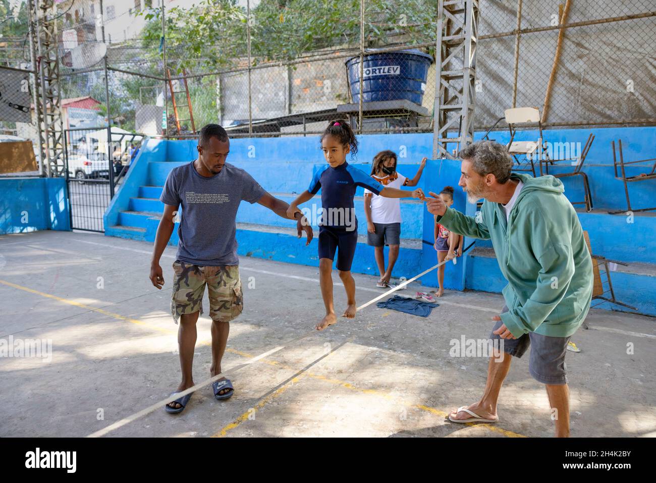 Brasile, Rio de Janeiro, Favela Babilonia, su iniziativa dell'associazione Maewan, e delle associazioni locali Favelasonha e Mawon nel corso di una cooperazione volta a promuovere lo sport nelle favelas, i due highliner Antony Newton e Pablo Signoret, campioni mondiali di highline multipli, Hanno installato un slackline di iniziazione nella palestra favela, Eloise, 8 anni, ancora in una muta sta facendo i suoi primi passi sulla linea di allentamento, La palestra è il luogo privilegiato di vita per questi bambini che non sono stati in grado di andare a scuola per 2 anni a causa della crisi COVID Foto Stock