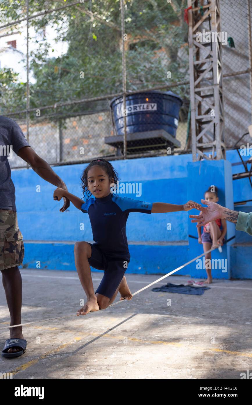 Brasile, Rio de Janeiro, Favela Babilonia, su iniziativa dell'associazione Maewan, e delle associazioni locali Favelasonha e Mawon nel corso di una cooperazione volta a promuovere lo sport nelle favelas, i due highliner Antony Newton e Pablo Signoret, campioni mondiali di highline multipli, Hanno installato un slackline di iniziazione nella palestra favela, Eloise, 8 anni, ancora in una muta sta facendo i suoi primi passi sulla linea di allentamento, La palestra è il luogo privilegiato di vita per questi bambini che non sono stati in grado di andare a scuola per 2 anni a causa della crisi COVID Foto Stock