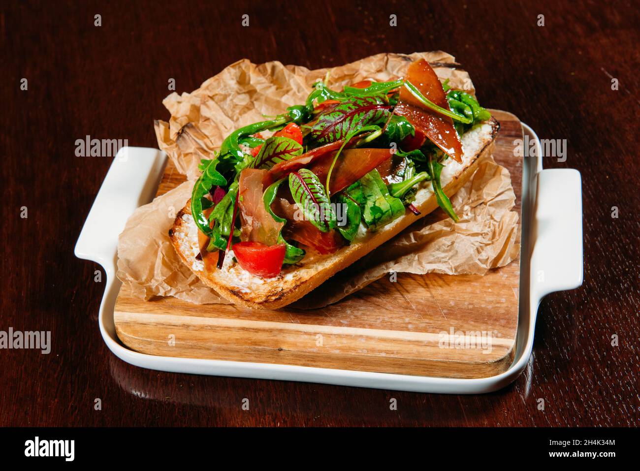 Pane tostato con prosciutto di parma, pomodoro, rucola e foglie di insalata Foto Stock