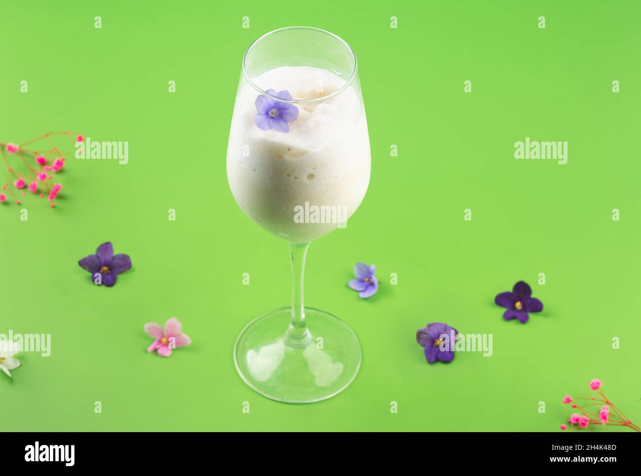 latte agitare cocktail bianco in bicchiere con frutti di bosco e fiori Foto Stock