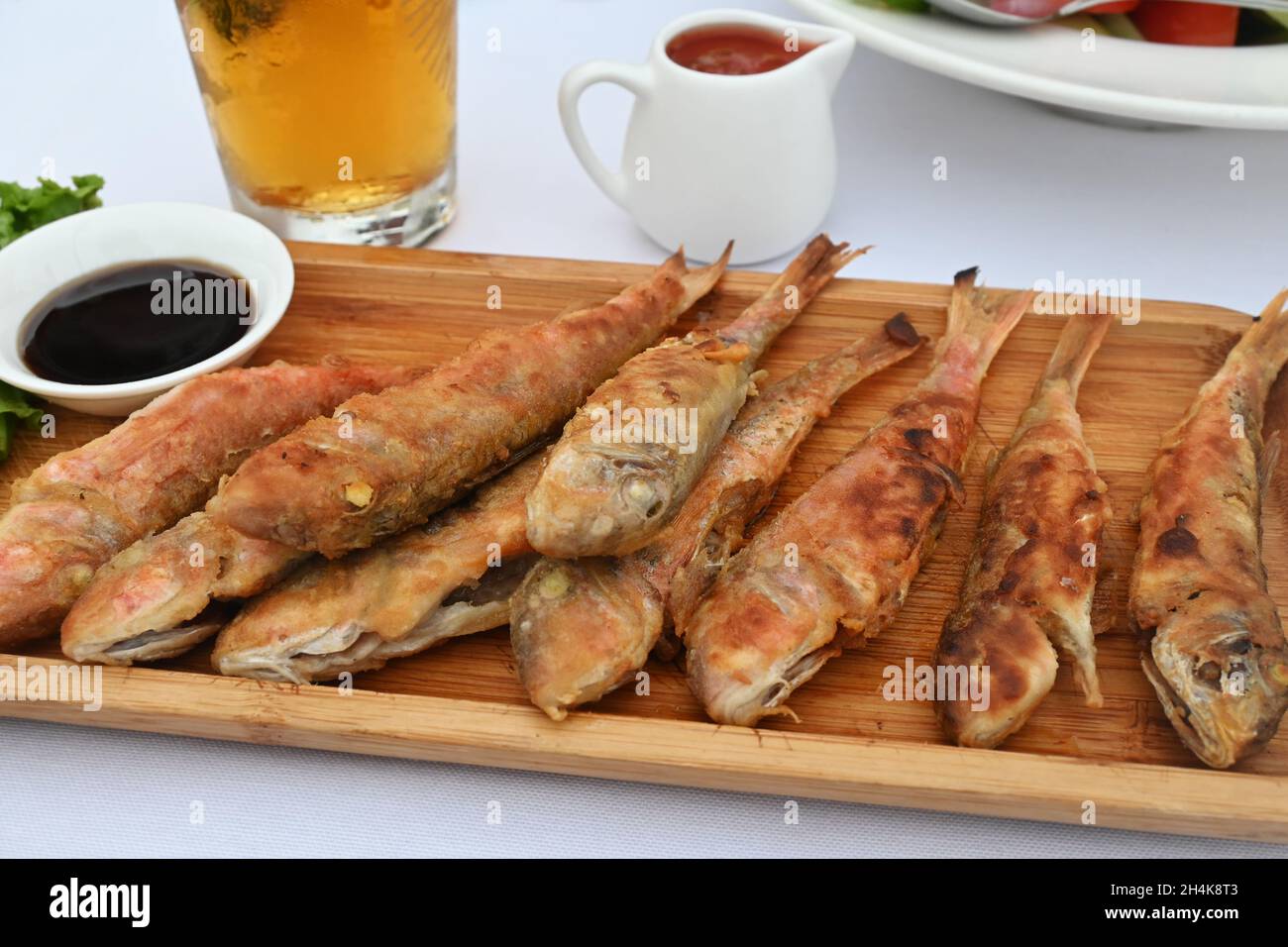 Piatto in legno di triglie fritte sul tavolo da pranzo Foto Stock