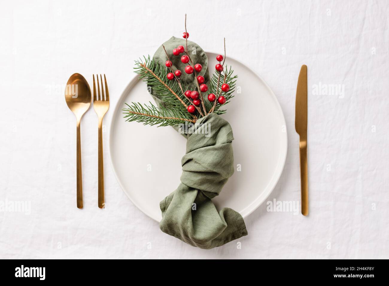 Tavolo di Natale con posate dorate su tovaglie di lino bianco. Foto Stock