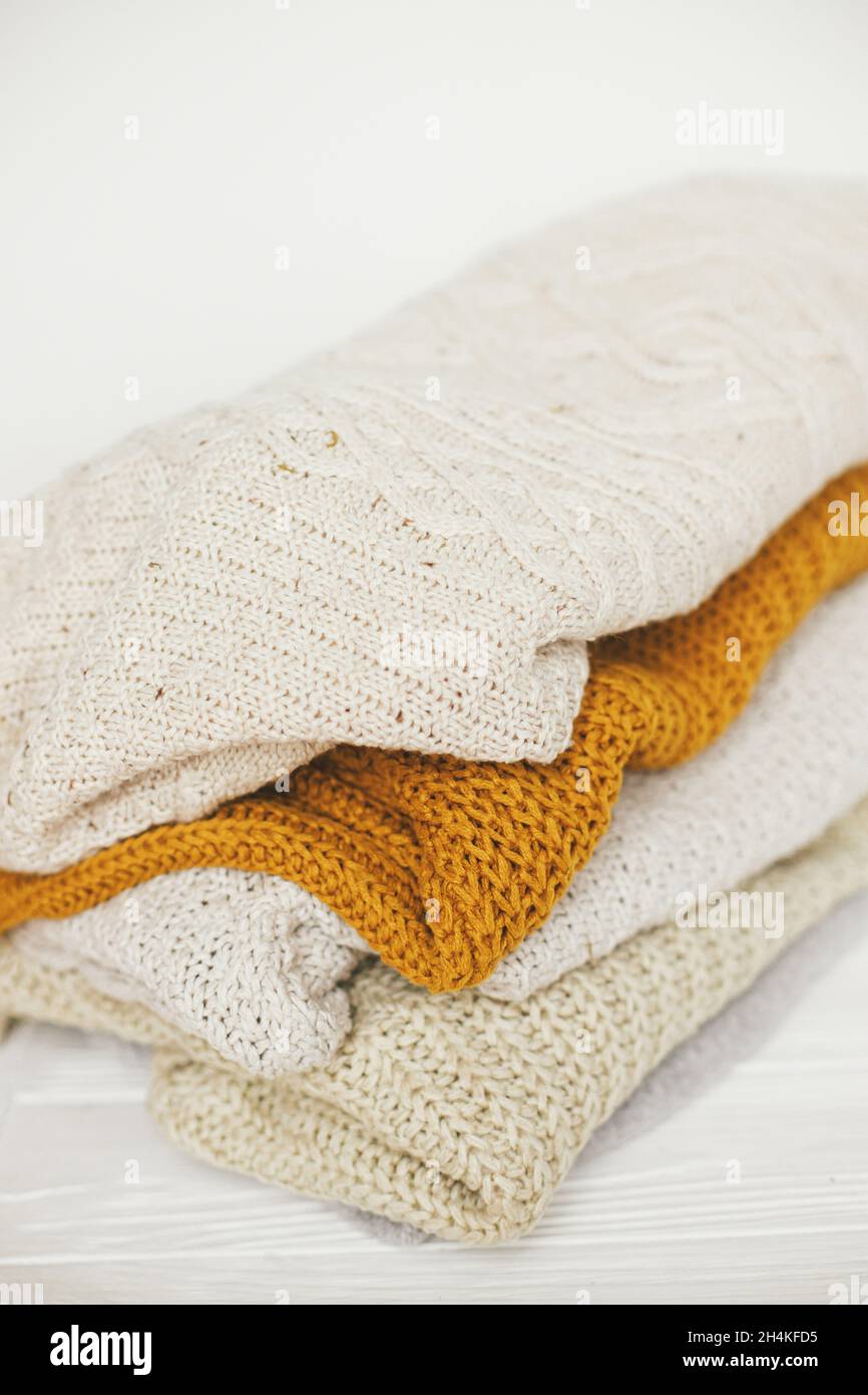 Un mucchio di maglioni bianchi, gialli e beige in maglia si avvicina in  bianco stanza scandinava. Maglioni a maglia accoglienti. Ciao autunno.  elegante guardaroba per i mari freddi Foto stock - Alamy