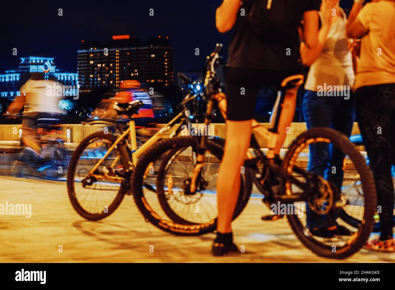 Gruppo astratto di ciclisti sulle strade della città di notte, gambe primo piano, ruote, biciclette. Concetto di sport, stile di vita moderno e sano, sfondo sfocato Foto Stock