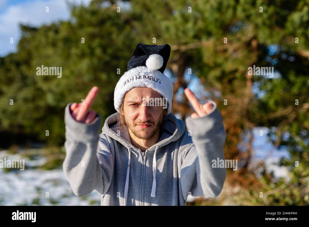 Un giovane uomo grumpy che indossa un cappello di santa nero con le parole Bah Humbug scritto su di esso Foto Stock