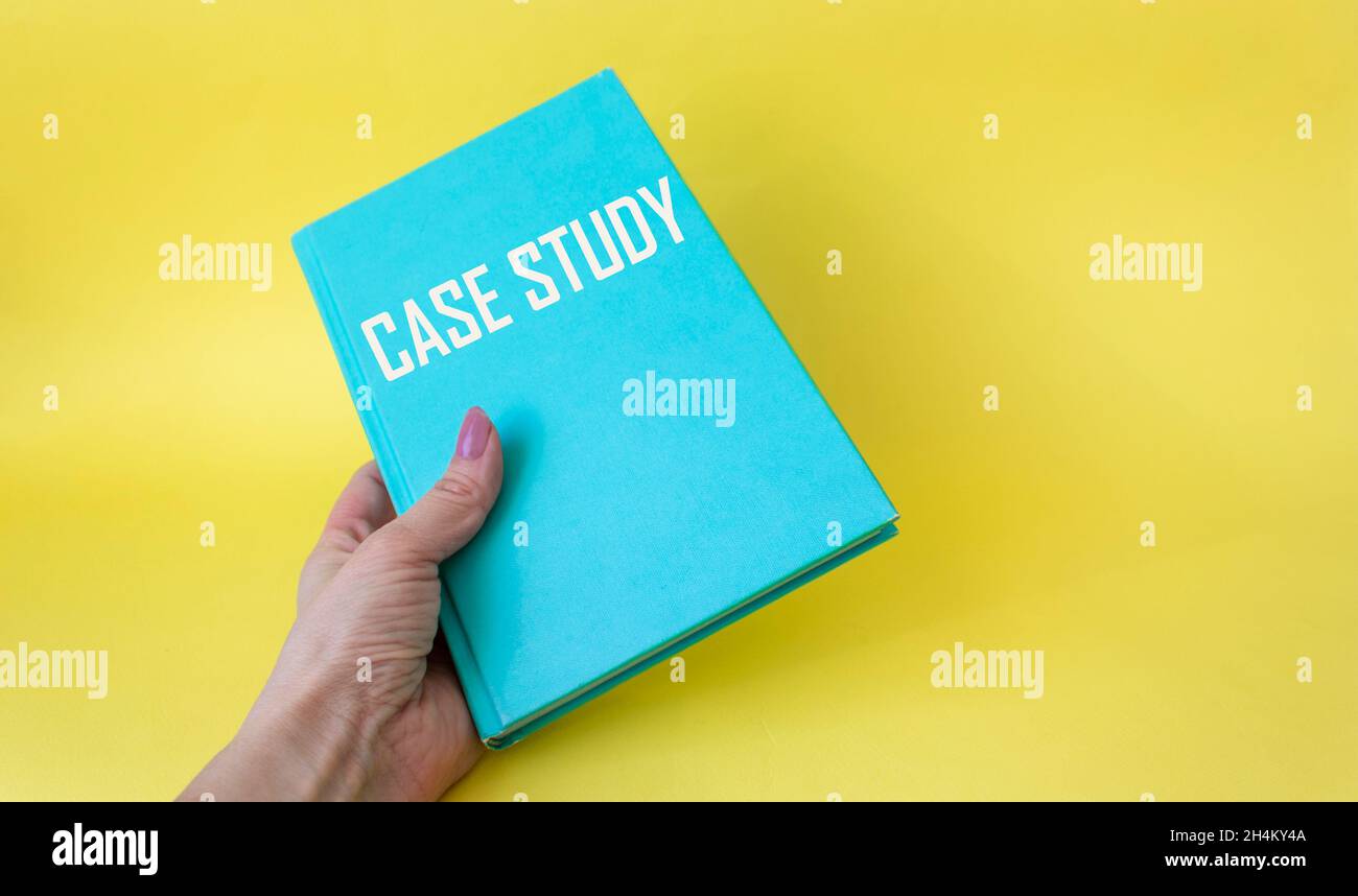 Testo del case study su un notebook verde in una mano femminile su sfondo bianco. Foto Stock