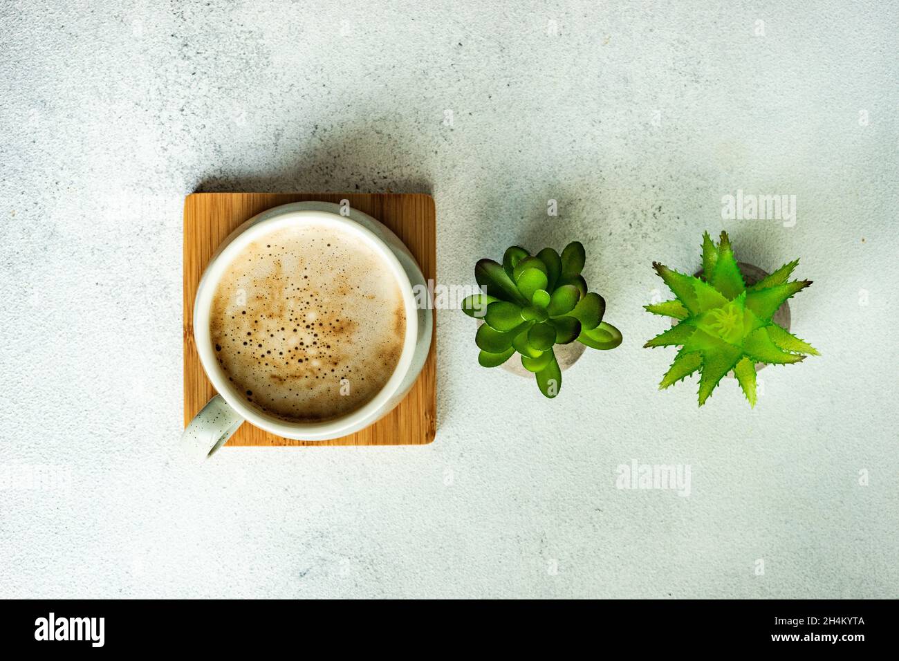 Tazza di caffè con latte e succulenti su tavola bianca moderna come un ambiente di lavoro Foto Stock