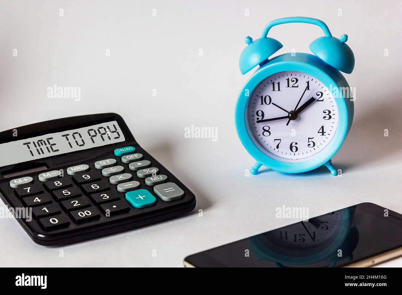 Testo Time to Pay sul display della calcolatrice, vicino alla sveglia e allo smartphone. Concetto commerciale e finanziario Foto Stock