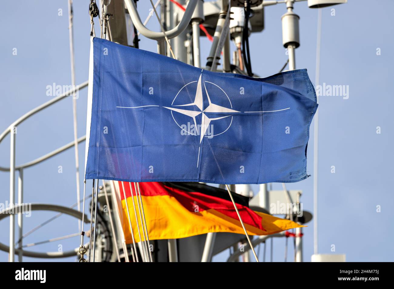 Bandiera dell'Organizzazione del Trattato del Nord Atlantico (NATO) che vola nel vento sull'albero di una nave da guerra Foto Stock