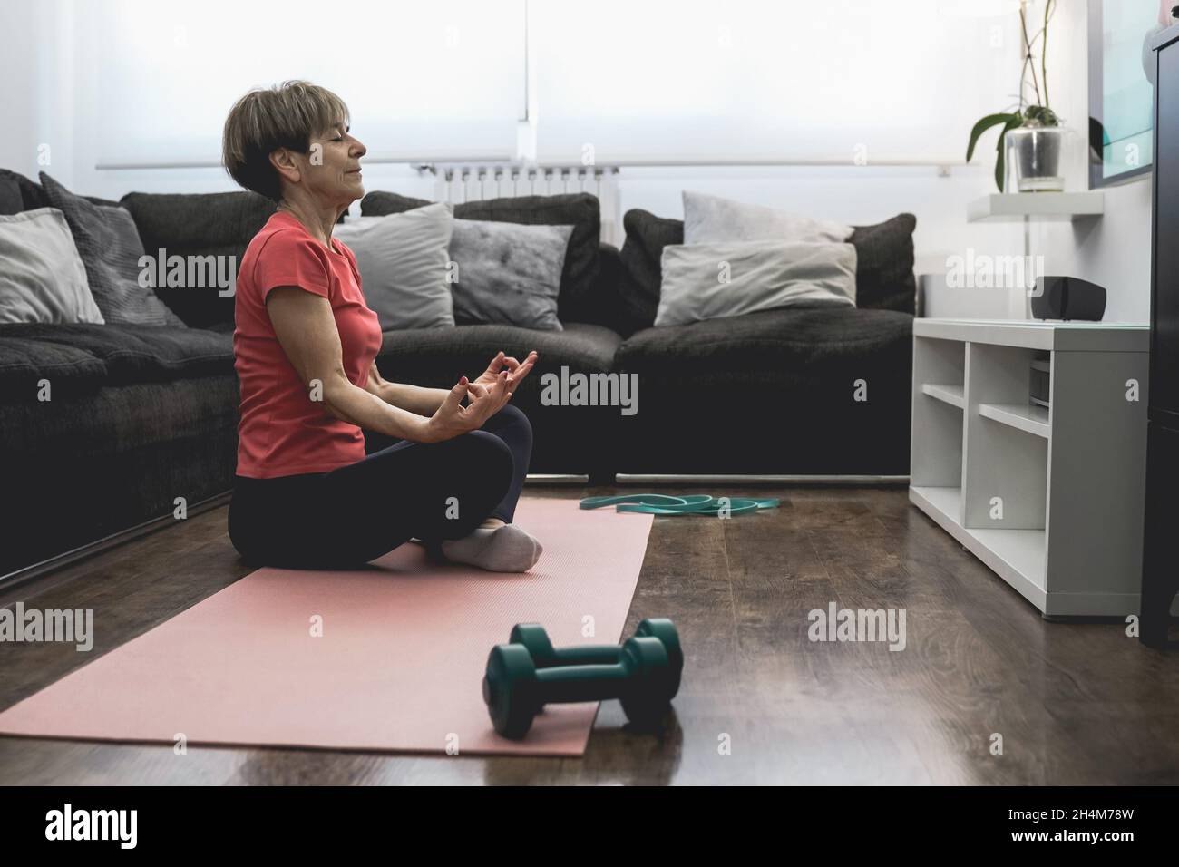 Donna anziana che fa online yoga sport allenamento classe a casa - sano e benessere anziano stile di vita concetto Foto Stock