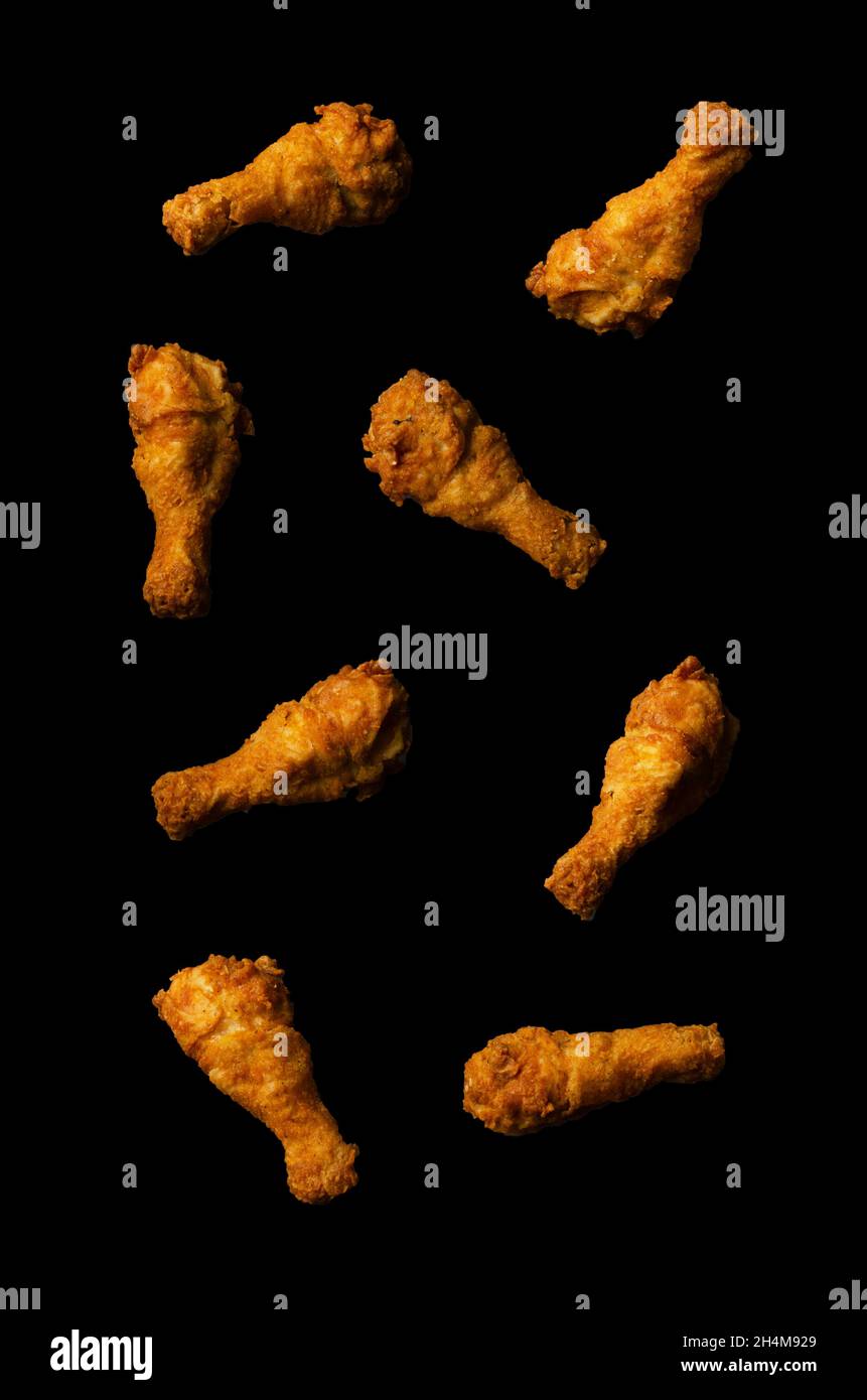 Cosce di pollo fritte che volano isolato su uno sfondo nero Foto Stock