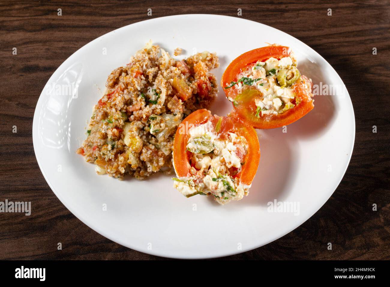 Insalata di tabbouleh con pomodoro ripieno. Cibo vegetariano. Piatto tradizionale medio-orientale o arabo. Vista dall'alto Foto Stock