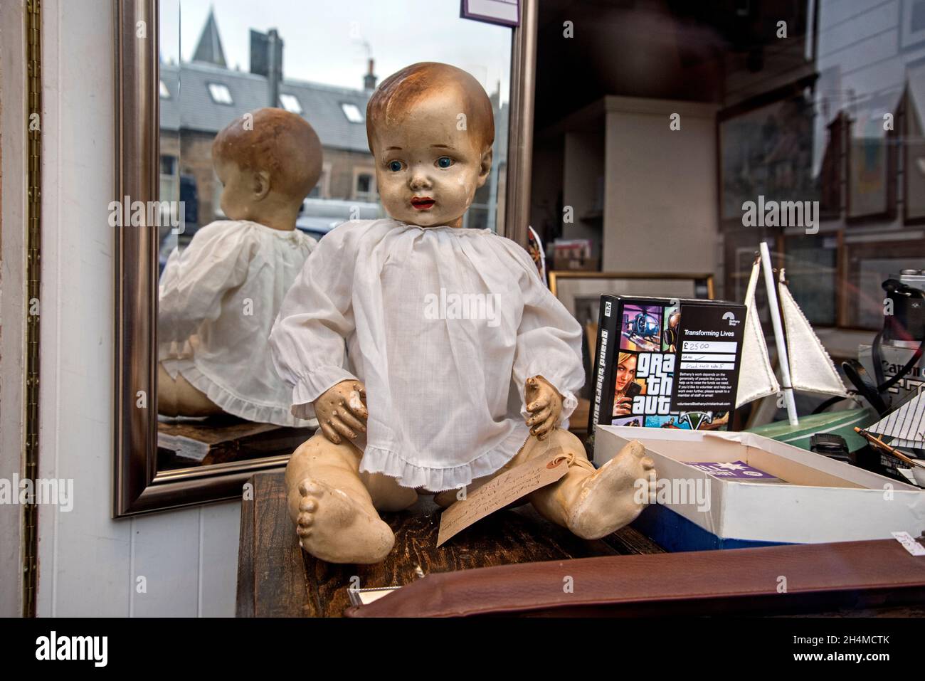 Bambola vintage anni '30 in vendita nella finestra di un negozio di beneficenza a Edimburgo, Scozia, Regno Unito. Foto Stock