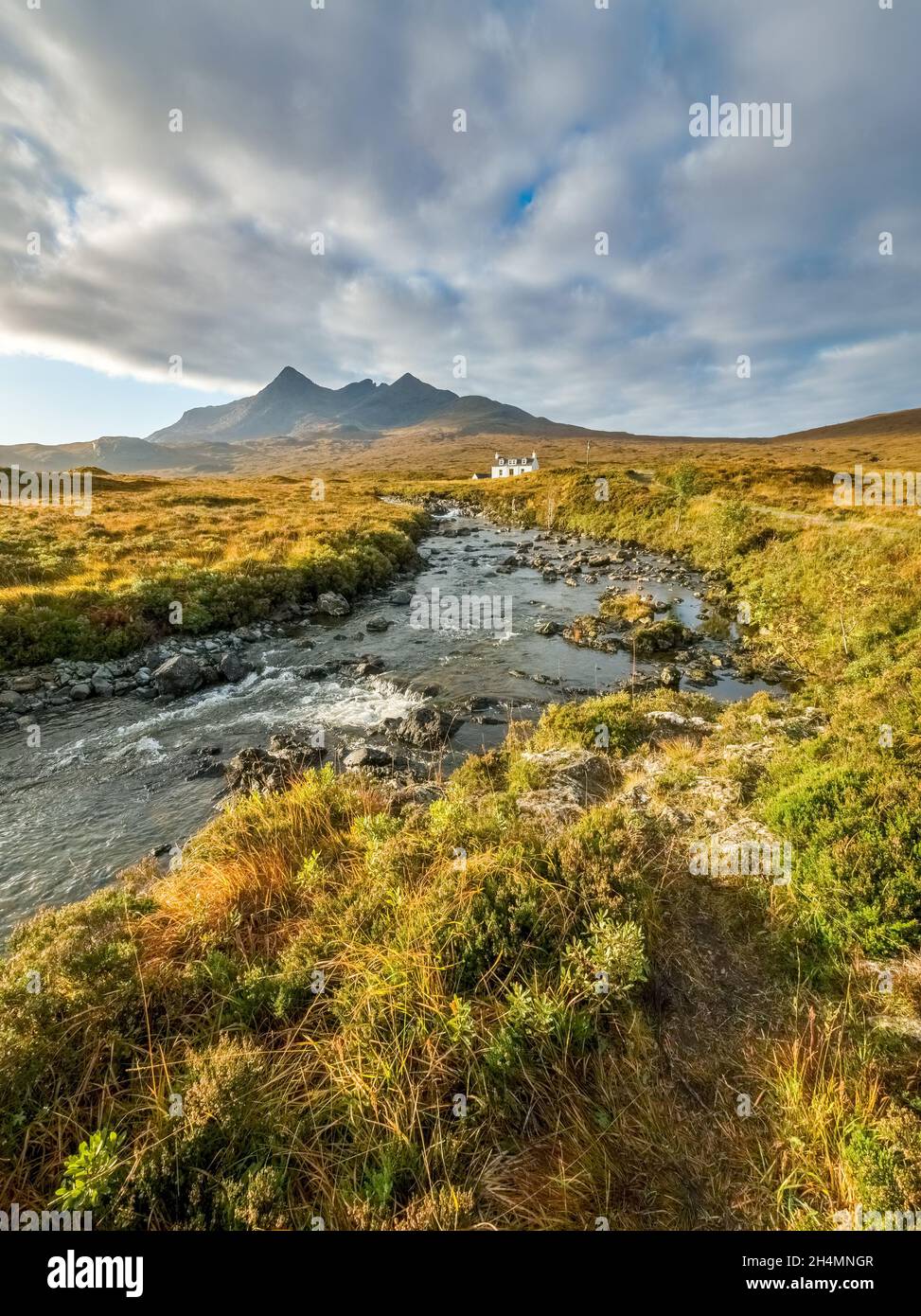 Casa bianca isolata (Allt Dearg House) a Glen Sligachan con le montagne di Cuillin nero oltre e la banca nuvola scura sopra, isola di Skye, Scozia. Foto Stock