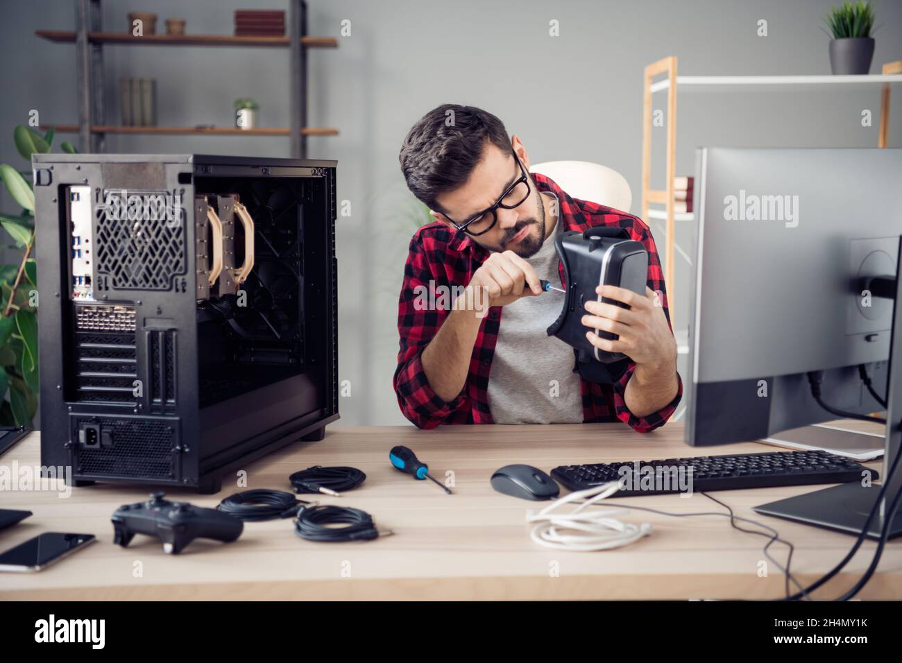 Ritratto di attraente intelligente e mirato ragazzo di fissaggio vr cyberspace dispositivo garanzia al coperto ufficio luogo di lavoro stazione Foto Stock