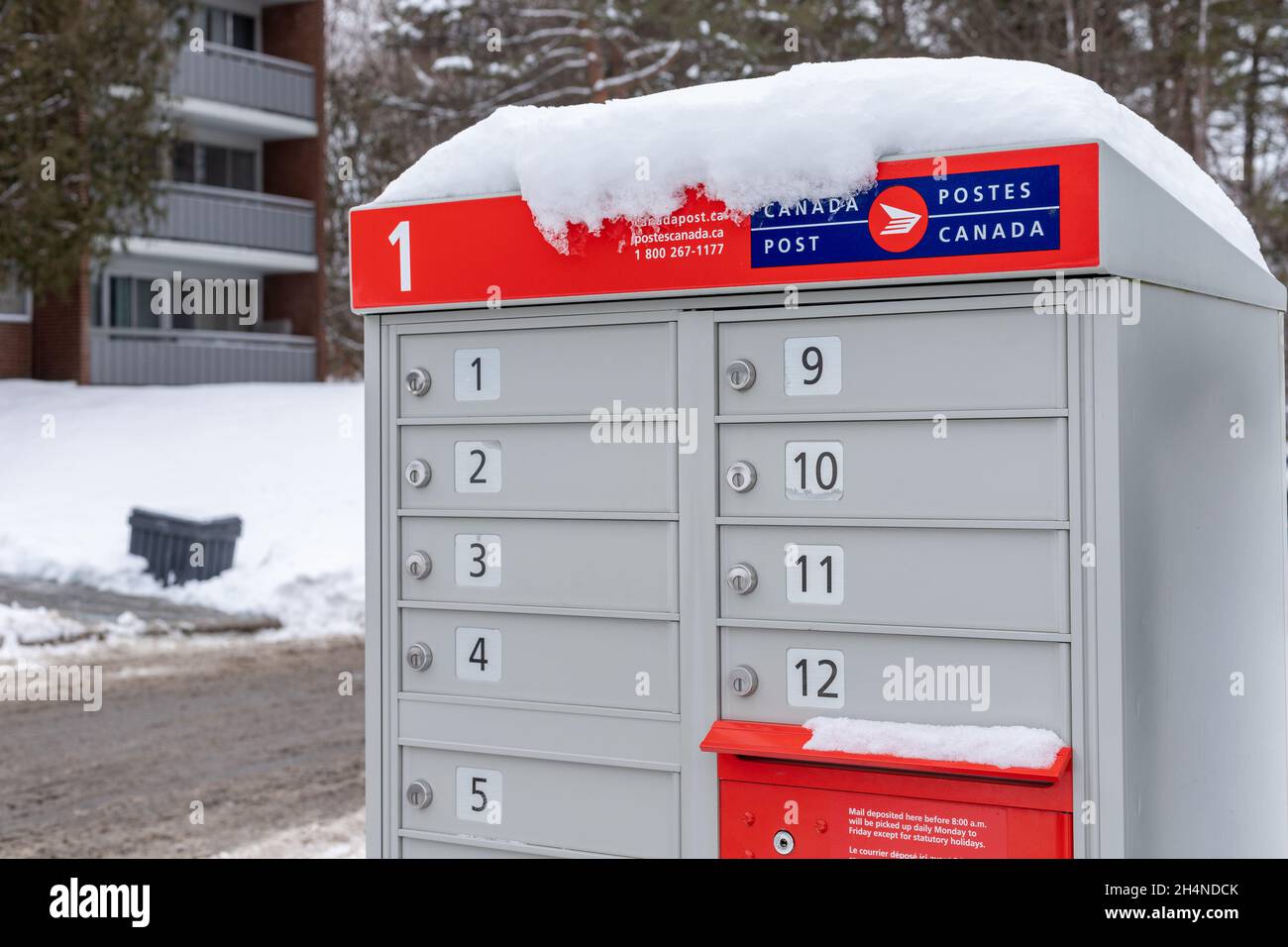 Canada posta caselle postali con segno rosso in inglese e francese vicino casa in inverno Foto Stock
