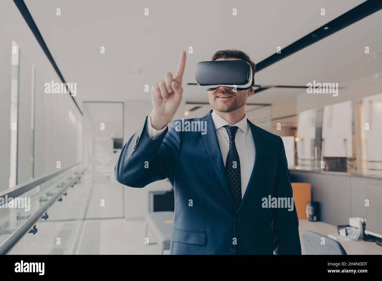Un imprenditore maschile sorridente che utilizza occhiali vr per la visualizzazione 3d, puntando con le dita Foto Stock