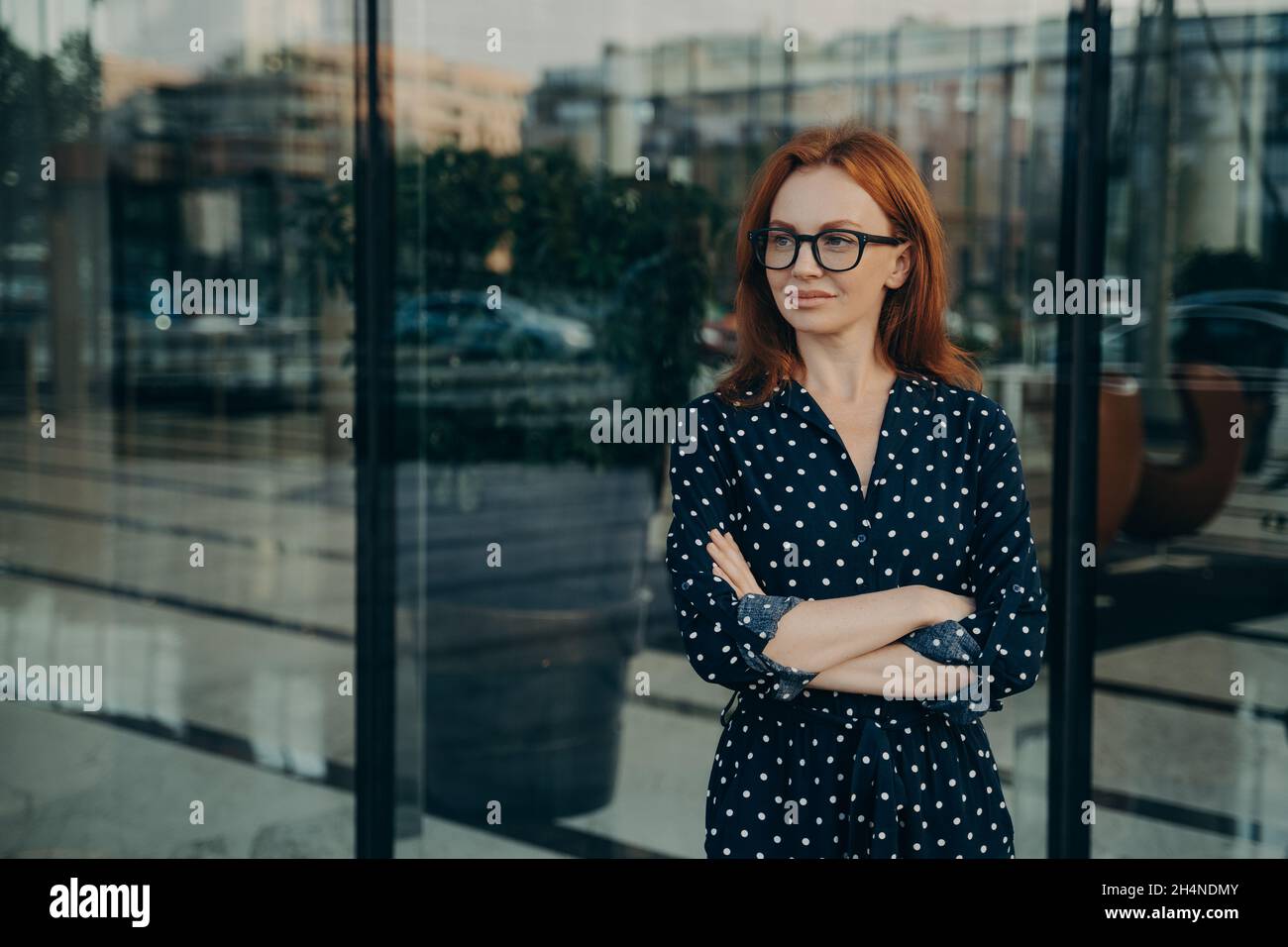 Buona donna rossa osservare giovane si alza vicino alla finestra dell'edificio dell'ufficio Foto Stock