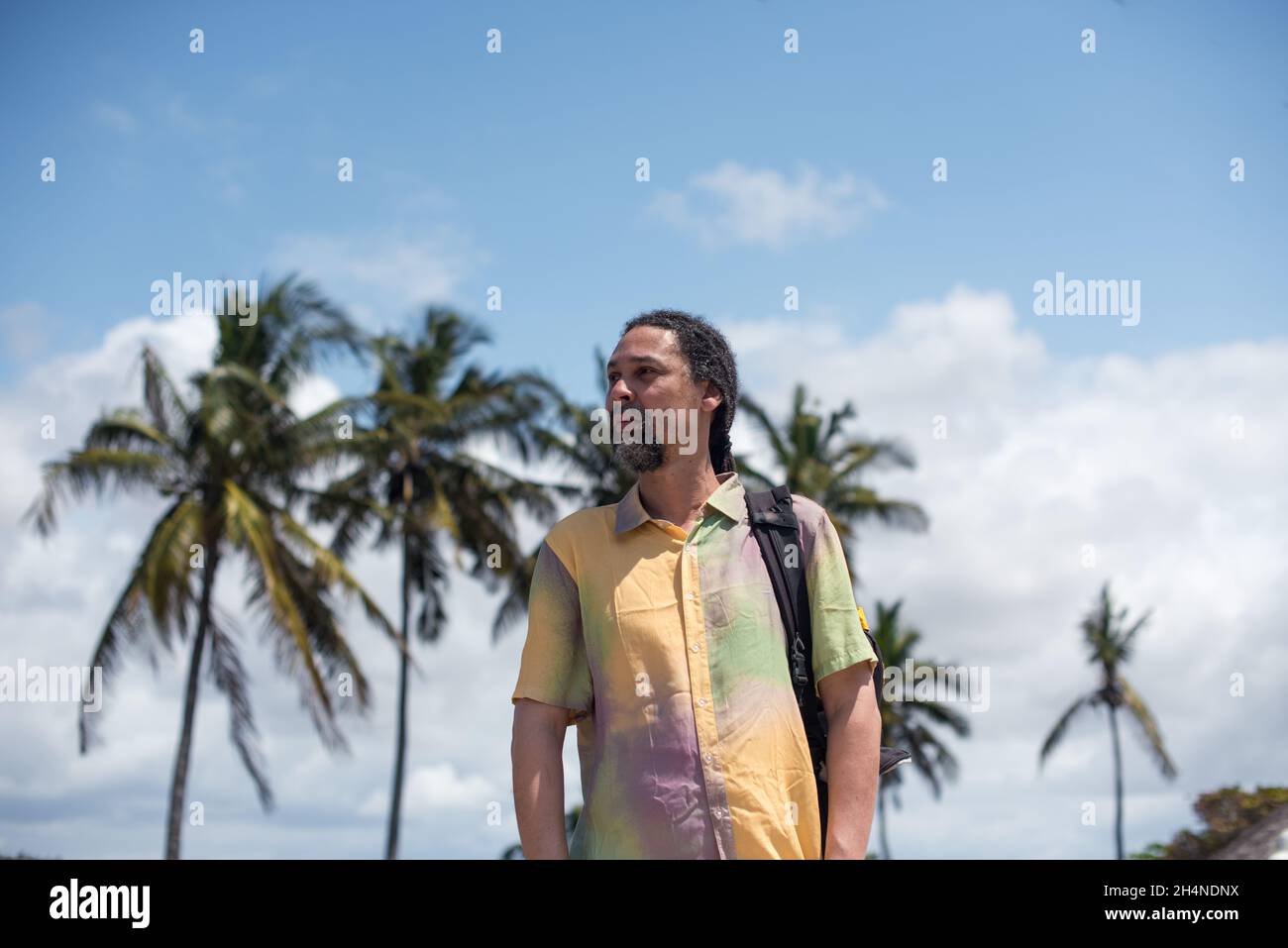 Uomo che guarda a lato con alberi di cocco sullo sfondo Foto Stock