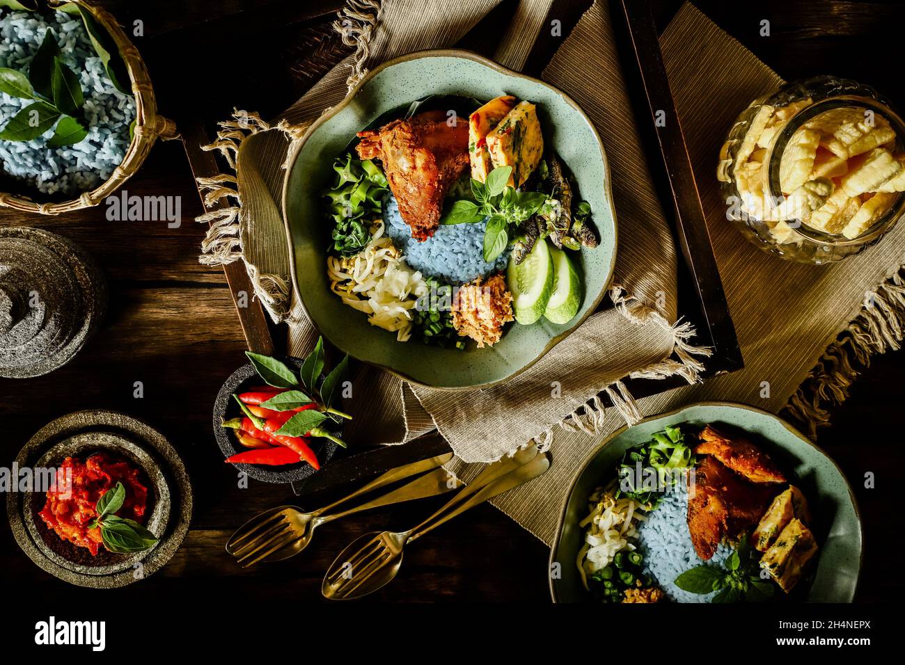 Nasi Kerabu. Riso al vapore con piselli a farfalla accompagnato da pollo alla griglia, omelette, insalata di verdure, acciughe, pasta di peperoncino e cracker. Foto Stock