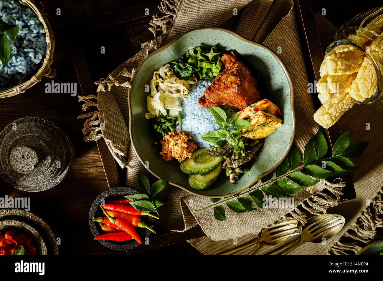 Nasi Kerabu. Riso al vapore con piselli a farfalla accompagnato da pollo alla griglia, omelette, insalata di verdure, acciughe, pasta di peperoncino e cracker. Foto Stock