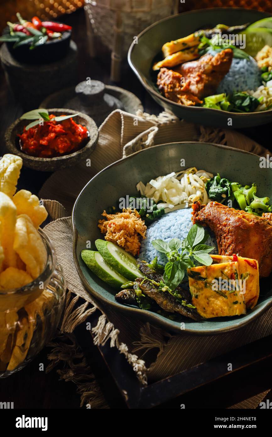 Nasi Kerabu. Riso al vapore con piselli a farfalla accompagnato da pollo alla griglia, omelette, insalata di verdure, acciughe, pasta di peperoncino e cracker. Foto Stock