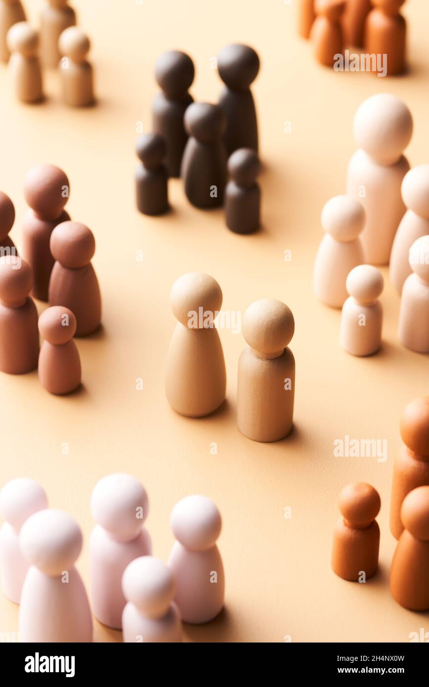 Dalle figurine di legno di stile minimalista sopra sopra di famiglie multirazziali che circondano la coppia senza bambino su sfondo beige Foto Stock