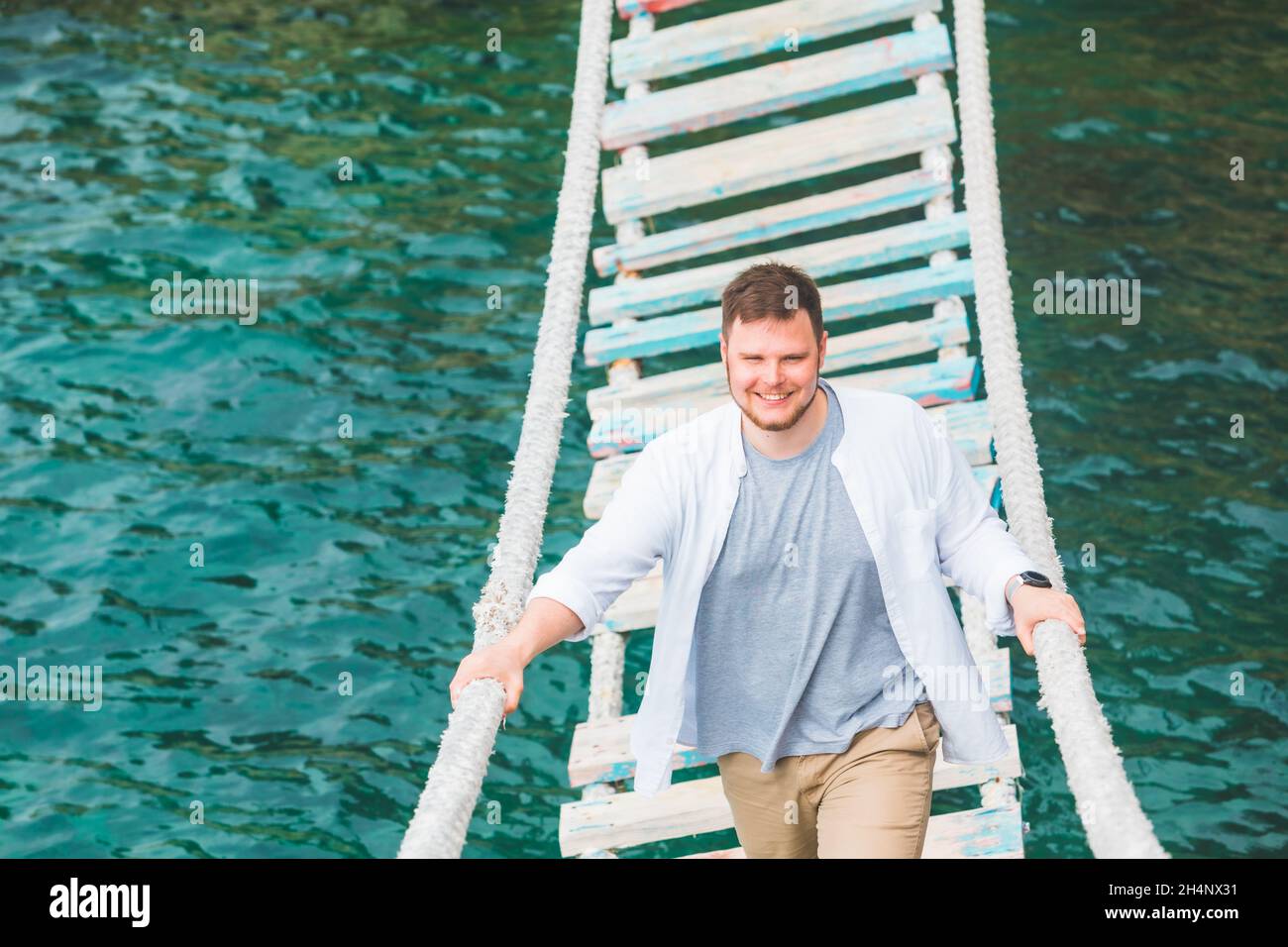 uomo a piedi da ponte sospeso attraversare adriatico mare ora estiva Foto Stock