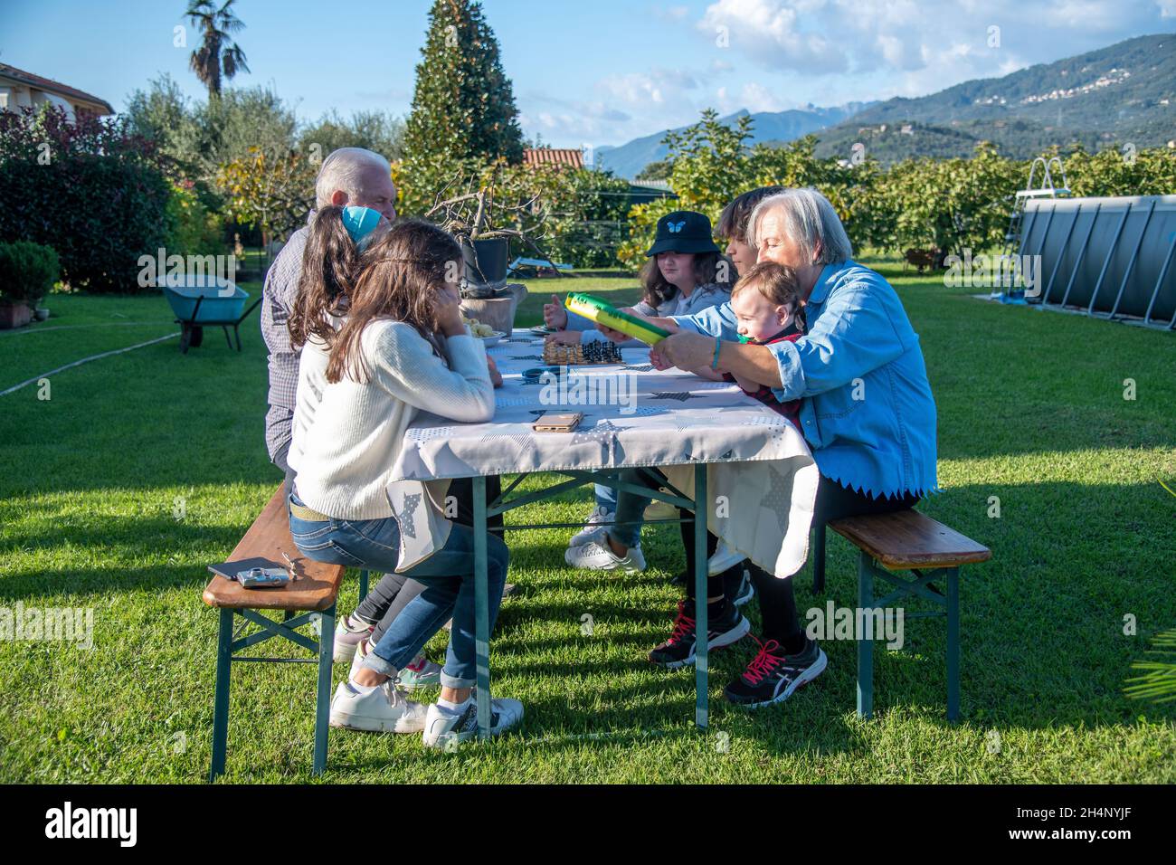 Nonni e nipoti che giocano insieme all'aperto in un pomeriggio di sole ai giochi da tavolo Foto Stock