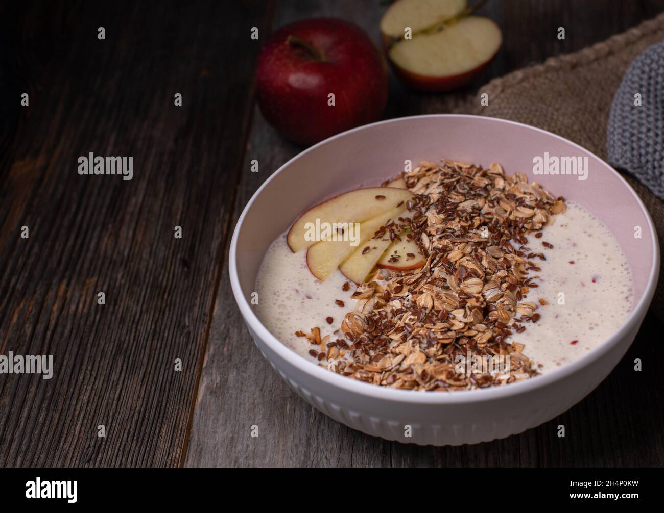 Una salubre ciotola per la colazione con yogurt fresco di mele, condita con fiocchi di avena arrostiti e semi di lino. Servito isolato su tavola di legno Foto Stock