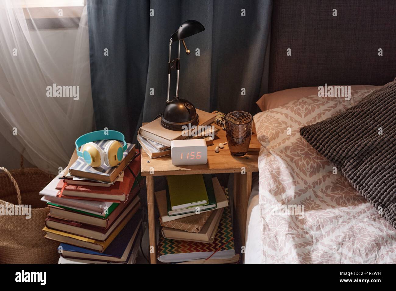 Immagine di un tavolo da letto con moderna sveglia e libri sotto il tavolo vicino al letto nella camera da letto Foto Stock