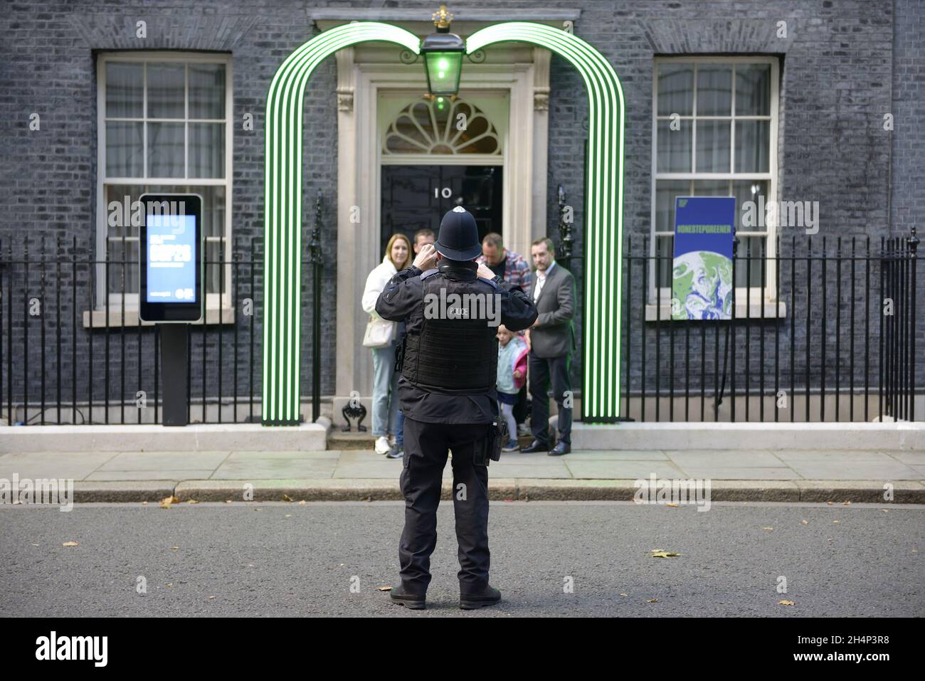 Londra, Inghilterra, Regno Unito. Poliziotto di Downing Street fotografando i visitatori di fronte alla porta del numero 10, residenza del primo Ministro Foto Stock