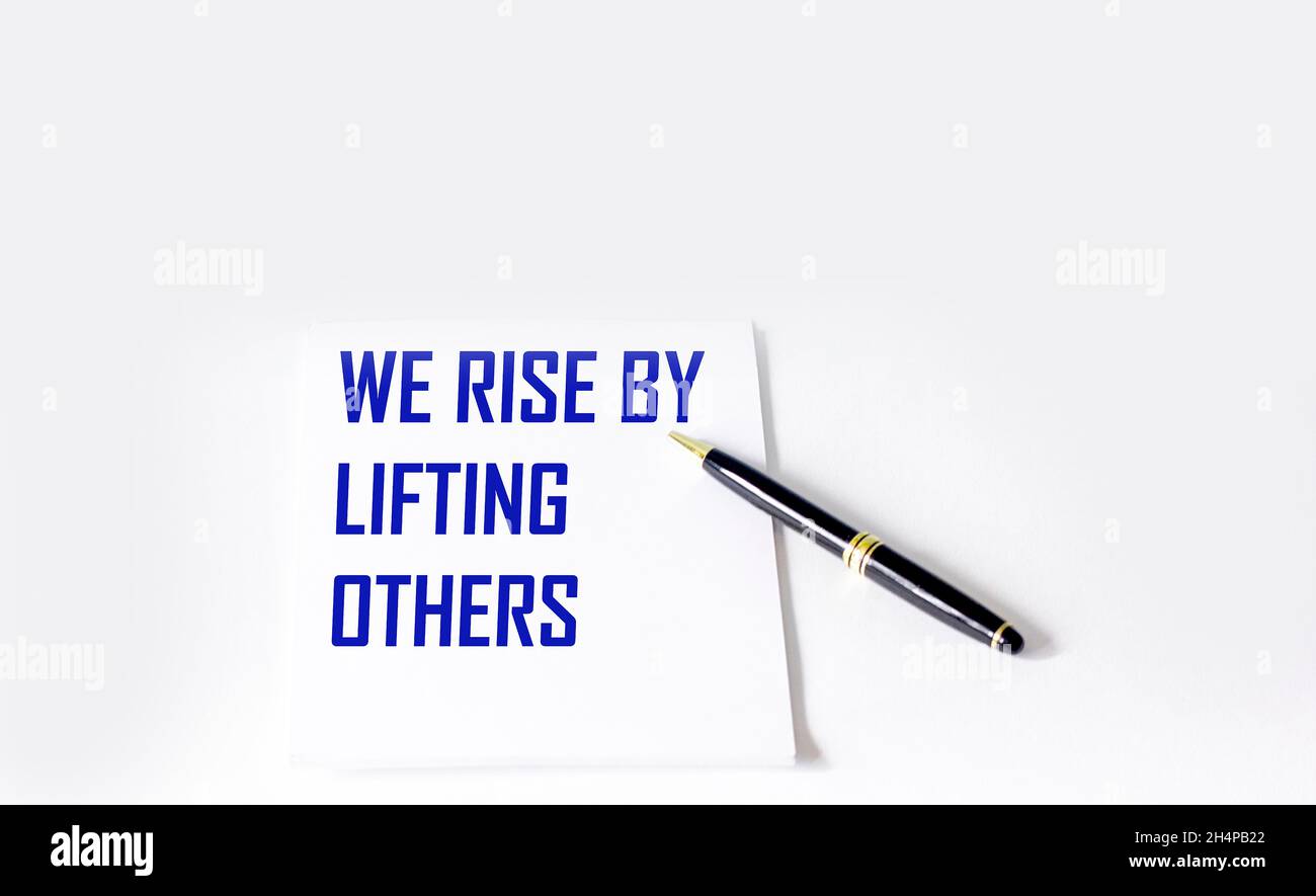 Citazione con l'iscrizione su un quaderno bianco sulla vita e sul lavoro che solleviamo aiutando gli altri Foto Stock