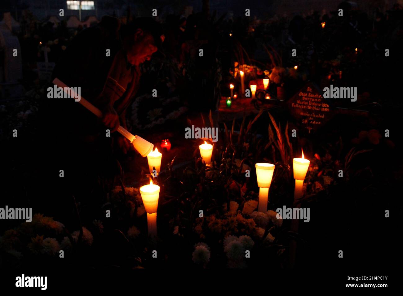 Non esclusiva: CITTÀ DEL MESSICO, MESSICO - 2 NOVEMBRE 2021: I membri della famiglia decorano e illuminano le tombe dei loro cari che riposano nel San Andrés Mixq Foto Stock