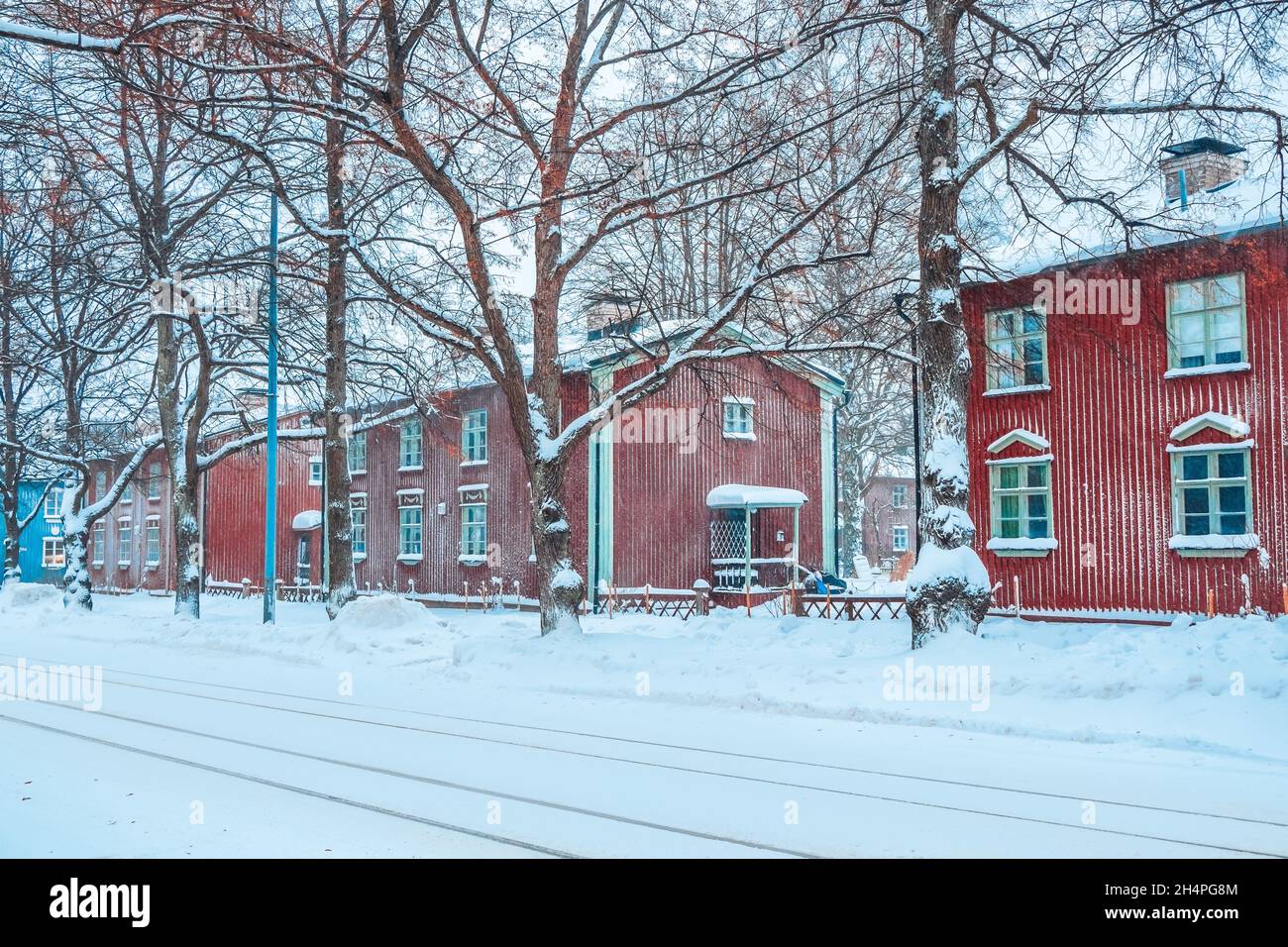 Bellissimo inverno finlandese in campagna. Vecchie case di legno rosso in Finlandia. Vista su una strada innevata dopo la nevicata. Facciate colorate dell'edificio Foto Stock