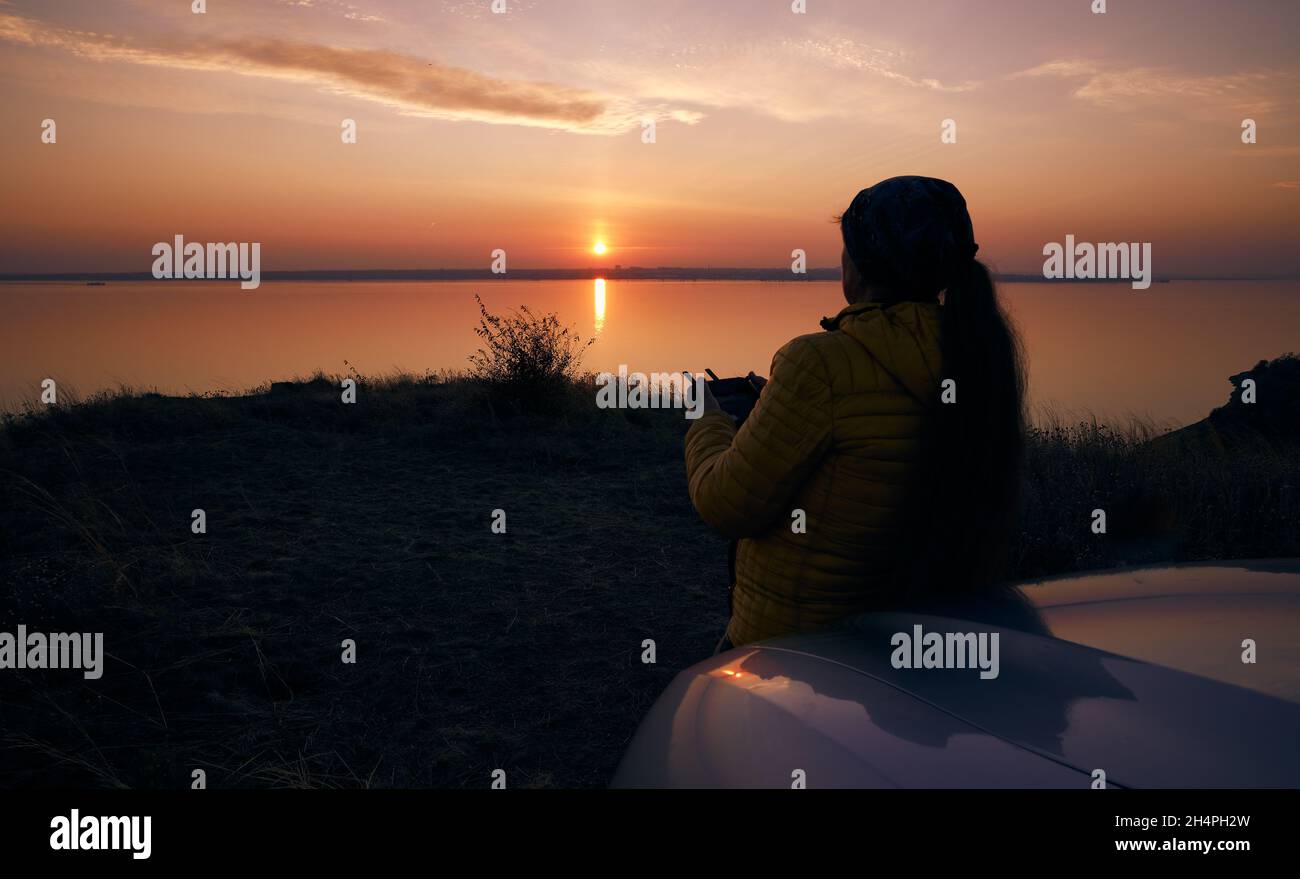 Tramonto e la figura di una donna dron telecomando in mani. Odessa Ucraina, estuario di Belgogr Dnestrovsky. Foto Stock