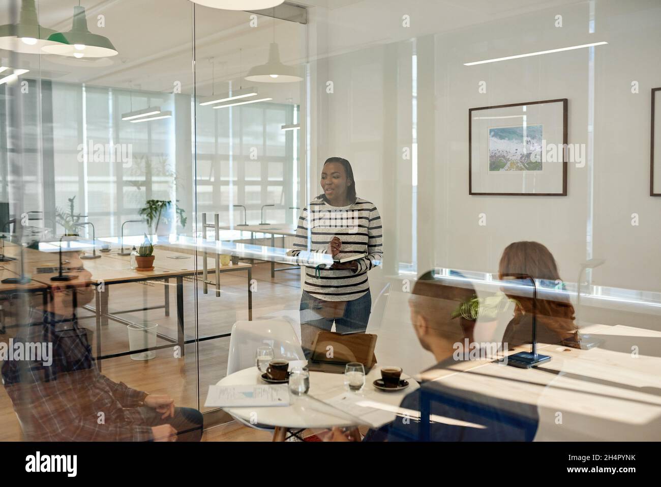 Uomo d'affari che parla con i colleghi seduti intorno a un tavolo in un ufficio Foto Stock