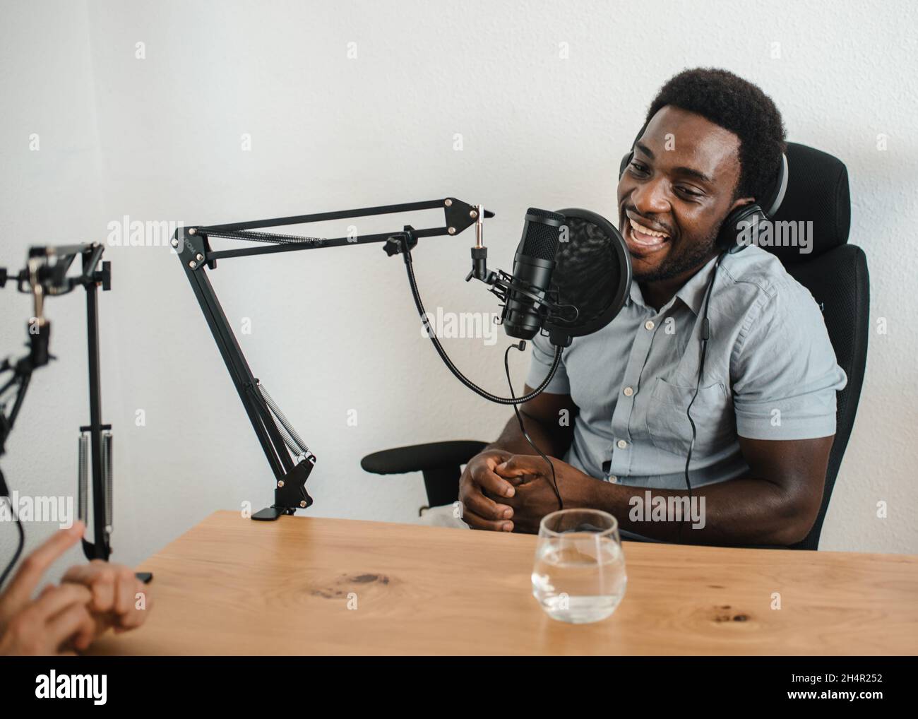 Uomo nero che registra podcast con crop collega Foto Stock