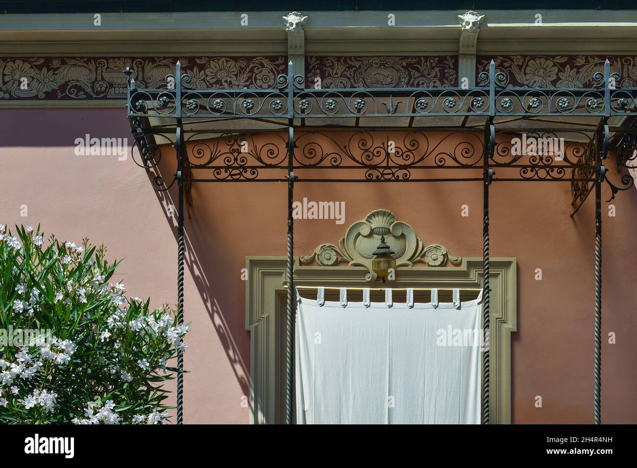 Esterno di una casa vacanze in stile Art Nouveau con una tenda alla finestra e una pianta di oleandro bianco fiorito in estate, Toscana Foto Stock