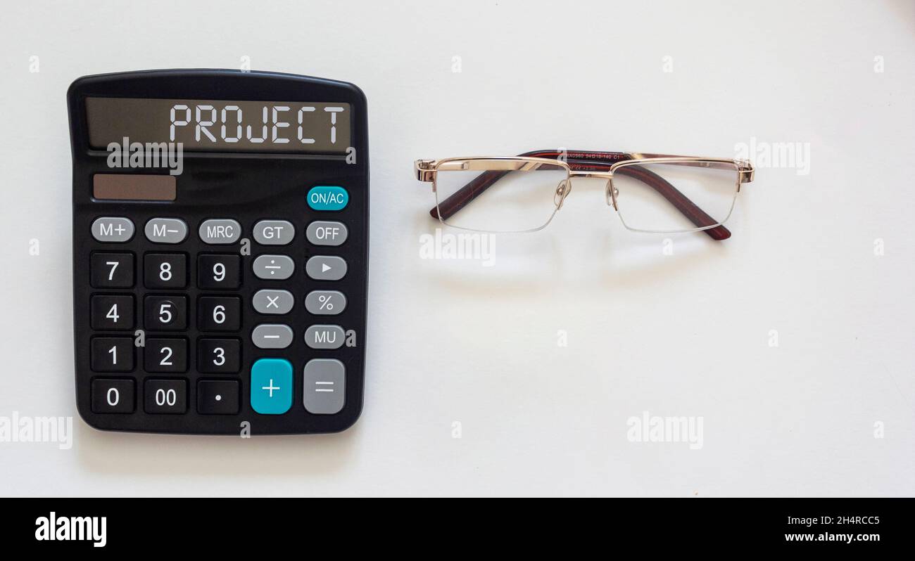 Iscrizione del progetto di testo su una calcolatrice e vetri su sfondo bianco. Progetto di creazione, idea, opzione per il futuro, la possibilità del suo i Foto Stock