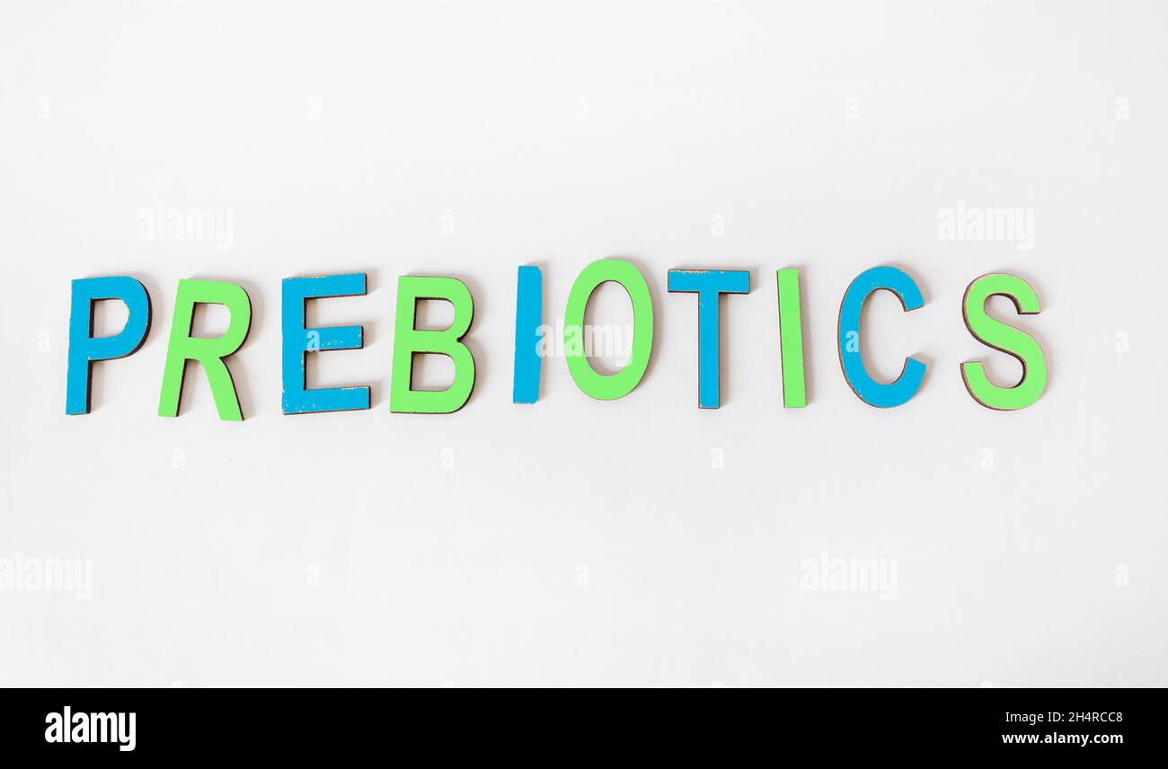 La parola PREBIOTICI è scritta in lettere di legno colorate su sfondo bianco. Foto Stock