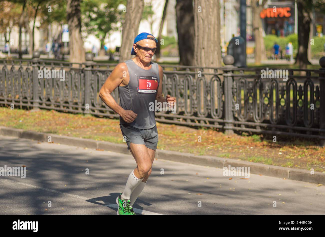 DNIPRO, UCRAINA - 26 SETTEMBRE 2021: Uomo anziano solitario che corre su una strada vuota della città durante 42 km di distanza di Almaz gruppo Dnipro Marathon Foto Stock